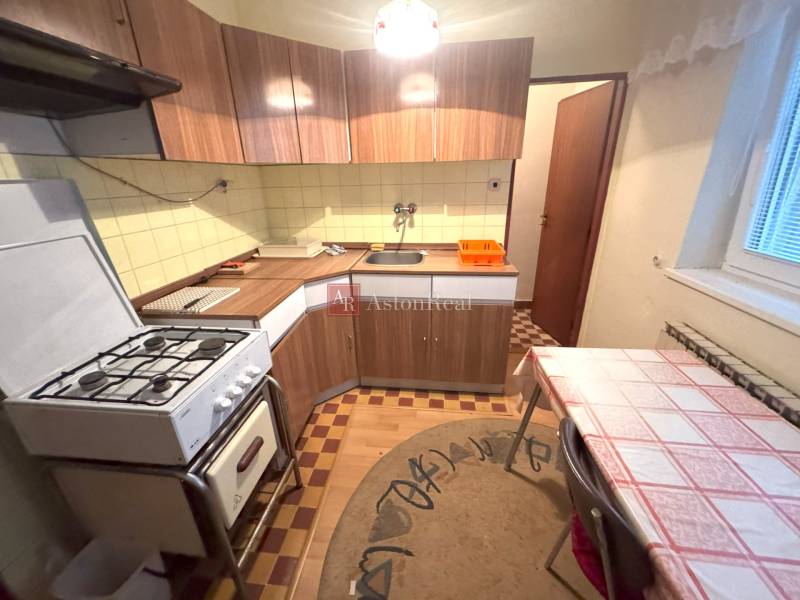 Kuchyňa v rodinnom dome s plynovým sporákom a podlahou s dreveným dekorom.