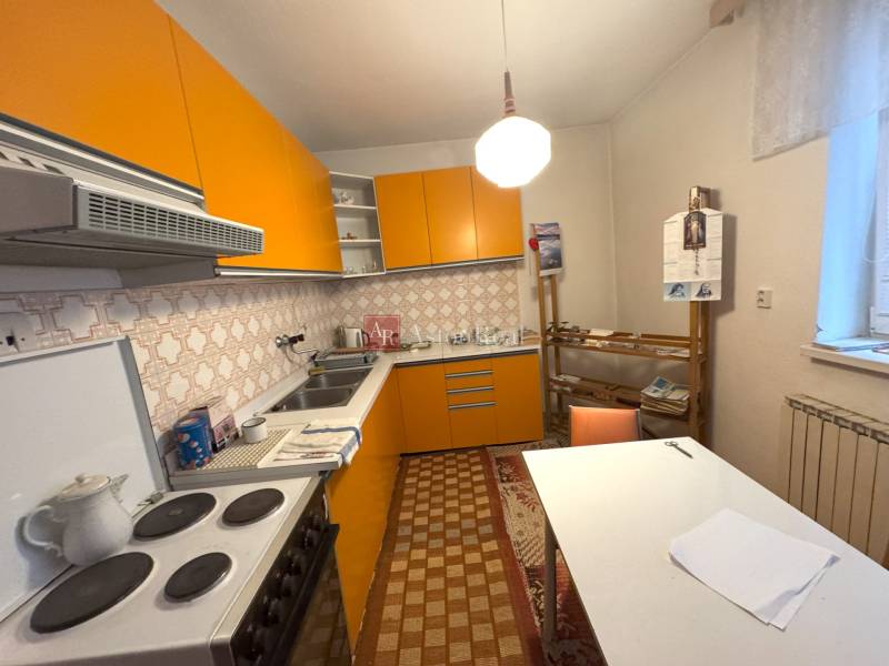 Kuchyňa v rodinnom dome s výraznými oranžovými skrinkami a retro dlažbou.